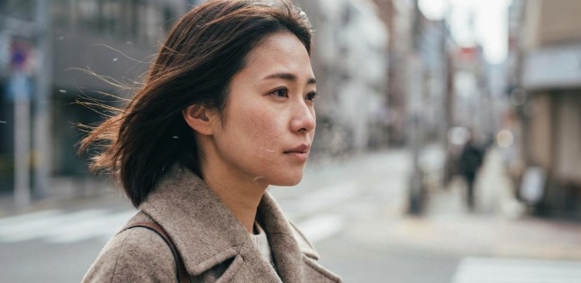 秋の冷たい風に吹かれながら街を歩く女性