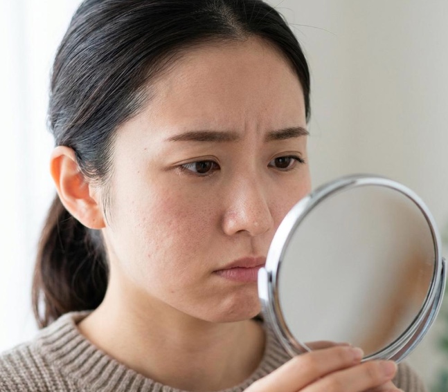 鏡の前で小鼻まわりの毛穴の状態を確認している女性