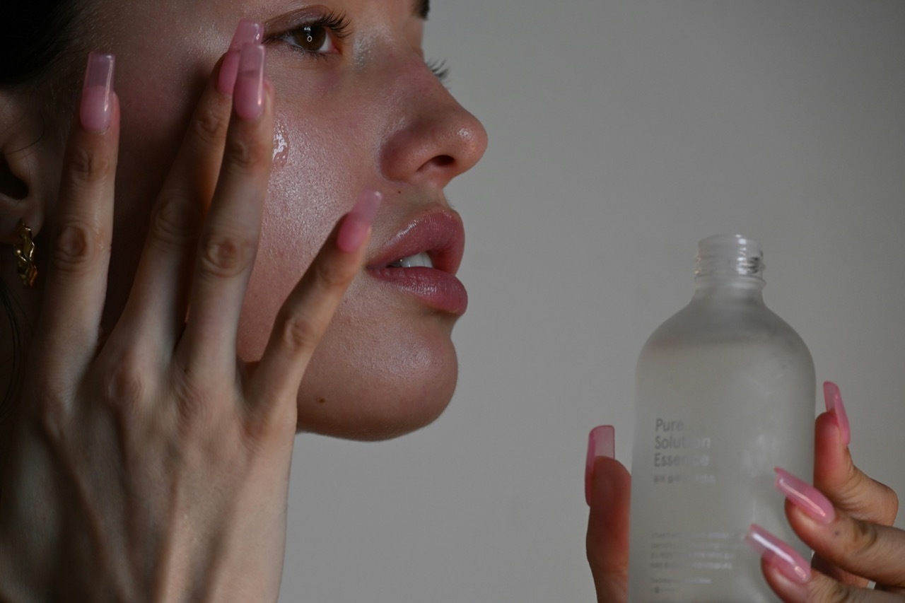 手のひらで頬に化粧水をなじませる女性