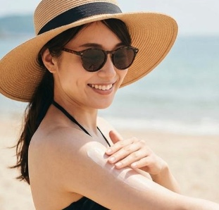 ビーチで日焼け止めを塗り直している女性