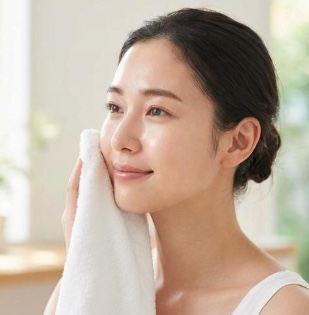 清潔なタオルで顔の汗を優しく押さえて拭き取る女性
