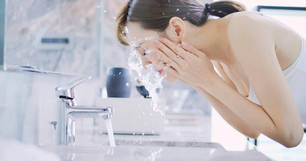 洗面台でたっぷりの水を使って顔をすすぐ女性